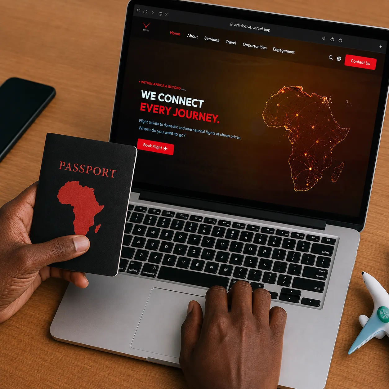 A passport in the shape of Africa beside a laptop showing a flight search